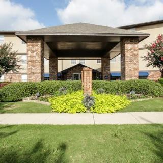 A residential building with a landscaped entrance and clear skies.