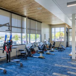 A modern gym with exercise equipment and ample natural light.