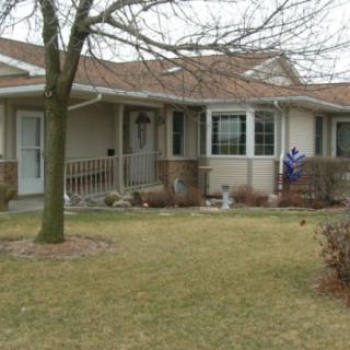 A suburban single-story house with a small front yard and trees.