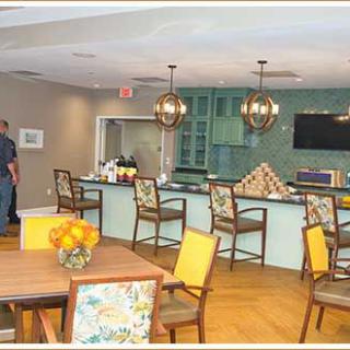 A modern kitchen and dining area featuring a bar counter with chairs, stylish lighting fixtures, and a television on the wall.