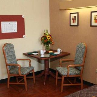 A cozy dining area featuring a small table, two chairs, and a vase of flowers against a warm-toned wall.