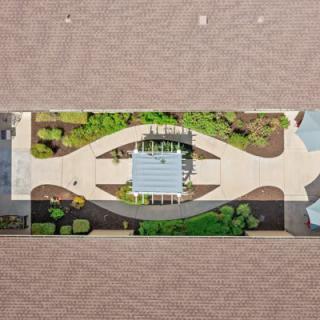 Aerial view of a landscaped garden with pathways and greenery surrounding a central structure.