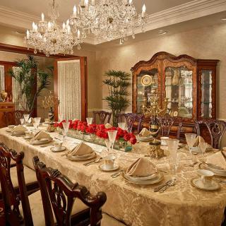 An elegantly set dining room with a luxurious table arrangement, complete with a crystal chandelier and china cabinet.