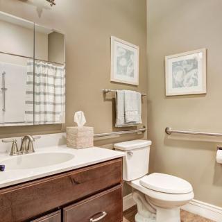 A cozy bathroom with neutral tones, featuring a sink, toilet, and decorative elements.