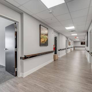 A clean and modern hospital corridor with open doors and a handrail along the wall.