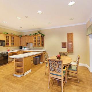 A modern kitchen with wooden cabinets, an island, and a dining area.