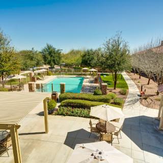 A serene outdoor pool area surrounded by lush greenery, perfect for relaxation on a sunny day.