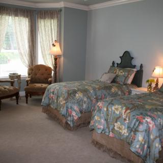 A cozy bedroom with twin beds, floral bedding, and elegant decor.