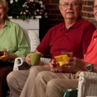 A group of seniors enjoying tea and conversation on a porch.