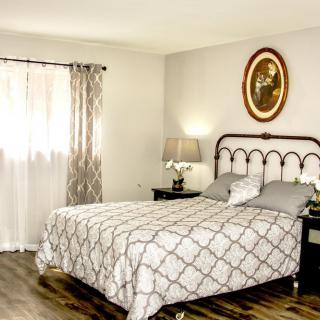 A cozy bedroom with a patterned bedspread, decorative lamp, and wall art.