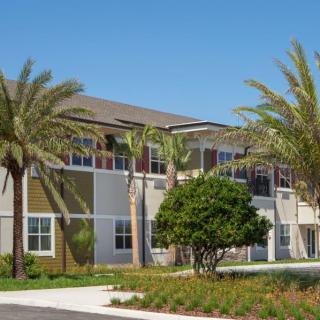 A modern residential building surrounded by palm trees on a sunny day.