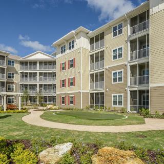 A modern residential apartment complex with well-maintained landscaping and multiple balconies.