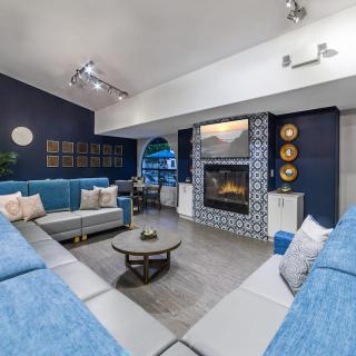 A modern living room with a blue color scheme, featuring a spacious seating area and a decorative fireplace.