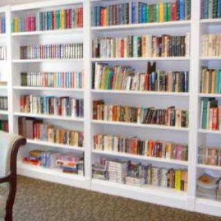 A cozy library with neatly arranged books on white shelves.