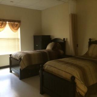 A cozy bedroom with two twin beds and a window adorned with curtains.