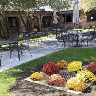 A cozy outdoor patio area with tables and chairs surrounded by a neatly landscaped garden featuring colorful flowers.