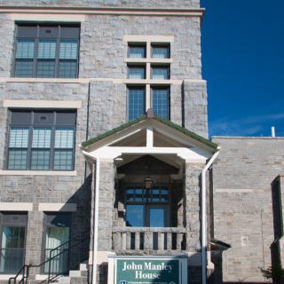 A historic stone building with a prominent entrance and a small balcony under a clear blue sky.
