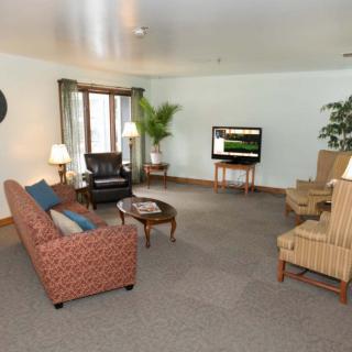 A spacious living room with a variety of seating options, a television, and decorative plants.