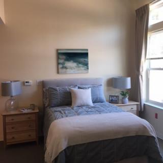 A cozy bedroom with a neatly made bed, two nightstands, and a large window.