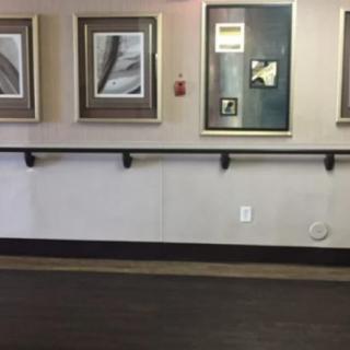A hallway featuring several framed paintings and a handrail.