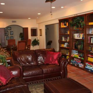 A cozy living room with leather furniture and a well-stocked bookshelf.