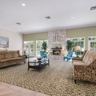 A spacious living room with elegant furniture, featuring a central fireplace and large windows.