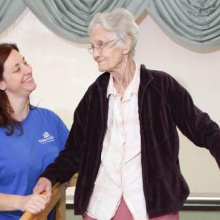 A caregiver assists an elderly woman, providing support and companionship.