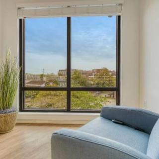 A cozy living room corner featuring a comfortable chair, a large window with a scenic view, and a potted plant.
