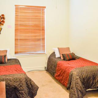 A cozy bedroom with two twin beds and a window with blinds.