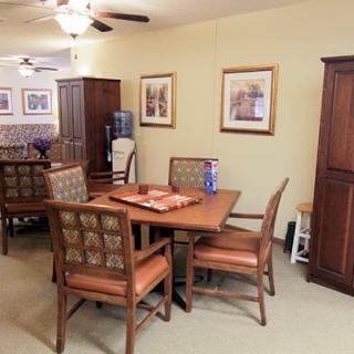 A cozy dining area featuring a wooden table and chairs, adorned with framed artwork on the walls and a water dispenser nearby.