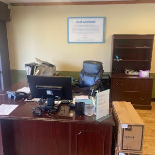 A view of a modern office workspace featuring a desk, computer, and organizational elements.