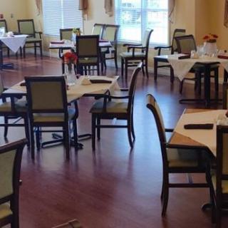 An empty dining room with neatly arranged tables and chairs on a wooden floor.