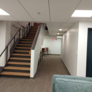A modern office hallway with a staircase leading to an upper level.