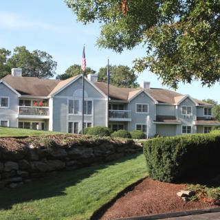 A view of a large residential building surrounded by neatly landscaped lawns and trees.