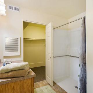 A bathroom with a shower and an adjacent closet, featuring folded towels on the counter.