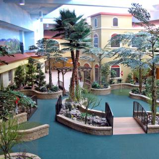 A beautifully designed indoor garden featuring palm trees and serene water pathways.