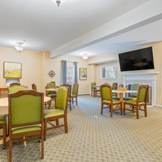A spacious dining room with tables, chairs, and a wall-mounted television.