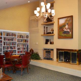 A cozy reading room with bookshelves, a fireplace, and elegant seating.