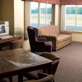 A cozy living room setup with a sofa, armchair, table, and large windows.