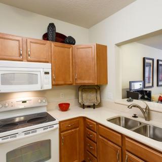 A modern kitchen with wooden cabinets, a microwave, stove, and double sink.