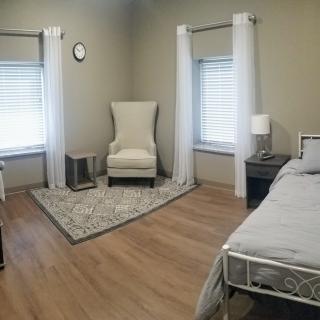 A minimalist bedroom with a cozy armchair, bed, and rug.