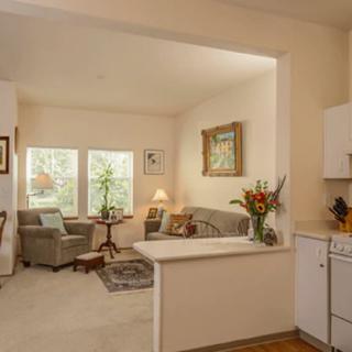 A cozy living room with an open-concept kitchen, featuring comfortable seating and abundant natural light.