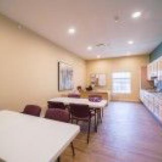 A well-lit kitchen with tables and chairs arranged for dining or meetings.