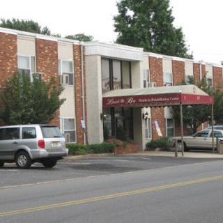 A view of a hotel building with brick facade and entrance awning, featuring parked vehicles in front.