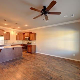 Open concept kitchen and living area with wood flooring and ceiling fan.