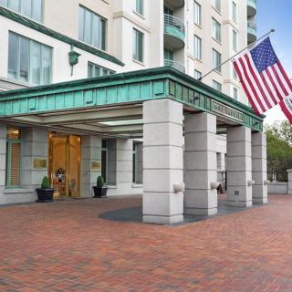 The entrance of a modern hotel with an American flag displayed.
