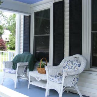 A cozy porch setup with wicker chairs and plants in a basket.