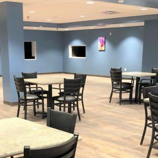 An empty dining area with tables and chairs against blue walls.