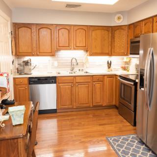 A modern kitchen with wooden cabinets, stainless steel appliances, and a hardwood floor.