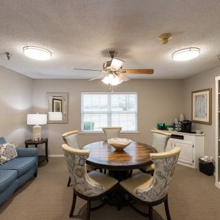 A cozy living and dining space featuring a round table with chairs, a sofa, and a ceiling fan.